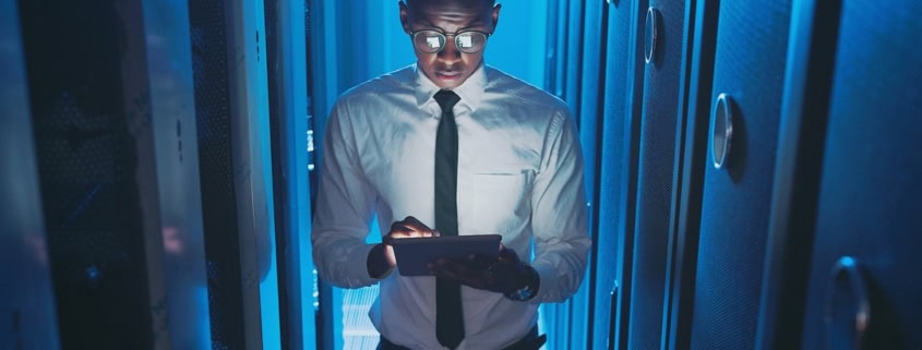 Tecnico IT con tablet nella sala server: controllo degli accessi ai sistemi aziendali.