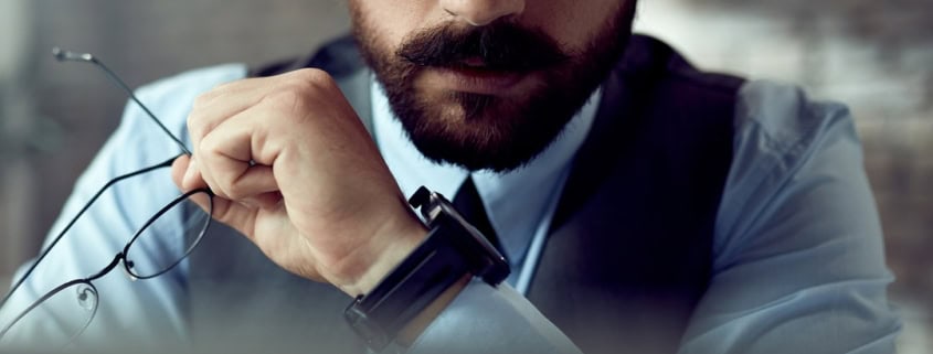 Professionista con gli occhiali in mano che osserva attentamente lo schermo del computer
