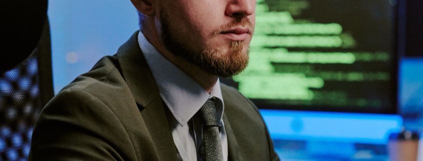 Professionista al computer con più monitor alle spalle in un ambiente di lavoro IT