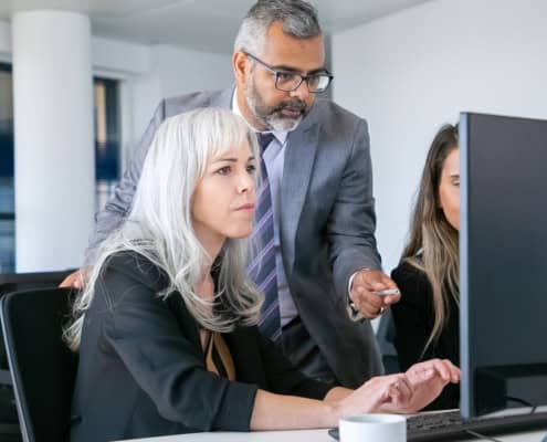 Colleghi in ufficio che esaminano insieme un monitor durante una riunione operativa